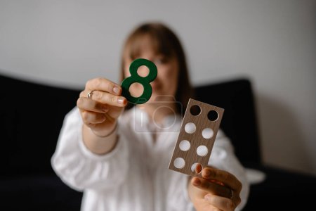 Photo for Young woman holding wooden numbers in her hands, face and background blurred - Royalty Free Image