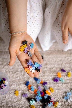 Photo for A multi-colored small cpuzzle set in a womans hands for the development childrens fine motor skills. Close up, blured background - Royalty Free Image