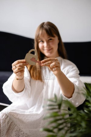 Foto de Una joven tiene en sus manos un rompecabezas de madera de una cerradura y una llave, se centran en la cerradura y el fondo borroso - Imagen libre de derechos