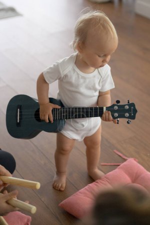 Photo for Little toddler girl playing ukulele in music class. - Royalty Free Image