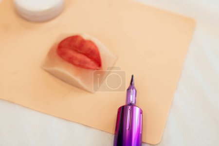 Maquillage permanent des lèvres. Esthéticienne en gros plan qui tatouait les sourcils. Maquilleur essayant de faire du maquillage permanent sur les lèvres en silicone. 