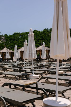 Belle plage vide avec chaises longues, tables et parasols blancs, été