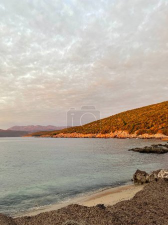 Evening view on small sand dune with green grass. Sandy beach at sea coast. Blue sky with white clouds. Sunset time. High quality photo