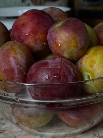 Sweet summer fruits of juicy plums in a clear plate. High quality photo