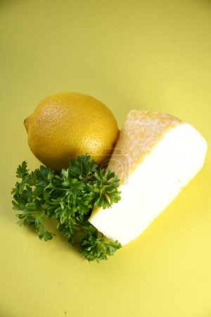 Käse, Zitrone, Grünzeug auf gelbem Hintergrund