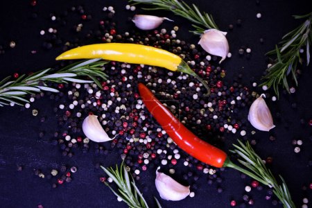 Seasonings to improve the taste of dishes. Pepper, garlic, rosemary on a black background.