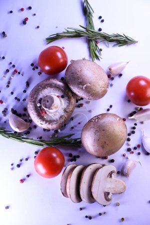 Champignon-Pilze auf grauem Hintergrund mit Paprika und Tomaten. Zutaten für ein vegetarisches Gericht