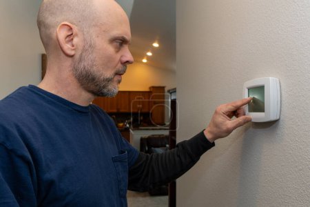 Heiminspektor begutachtet Thermostat in Wohnzimmernähe.