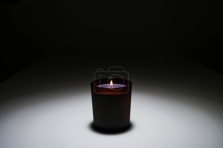 brennende Kerze im Dunkeln auf einem weißen Tisch