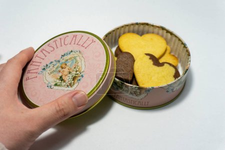 Photo of opening the lid of a cookie tin