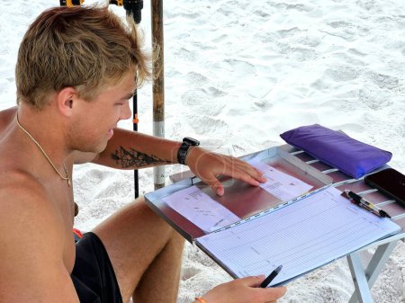 Young business man doing paperwork under beach umbrellas for tourism. 