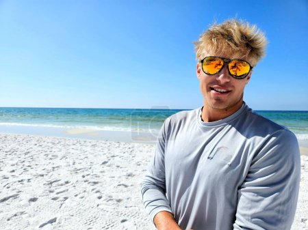 Téléchargez les photos : Cool surfeur garçon posant sur la plage dans des lunettes de soleil réfléchissantes. - en image libre de droit