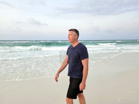 Single generation X man walking down the beach in morning routine on gulf coast of Florida. 