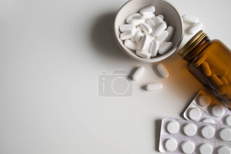 Photo for White pills in bowl, spilled from bottle and white tablets in blisters on white background - Royalty Free Image