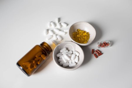 Many different pills and capsules on white background