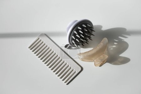 Haarkamm, Kopfhaut-Massagegerät und Haarclip auf weißem Hintergrund