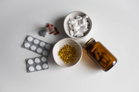 Muchas píldoras y cápsulas diferentes sobre fondo blanco