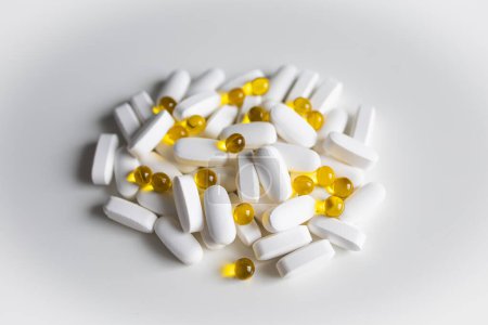 Una pila de píldoras y cápsulas blancas y amarillas sobre blanco