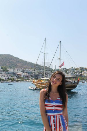 Beautiful young woman at the pier with boats and yachts in summer Turkey