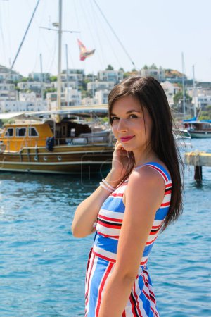 Belle jeune femme à la jetée avec des bateaux et des yachts en été Turquie