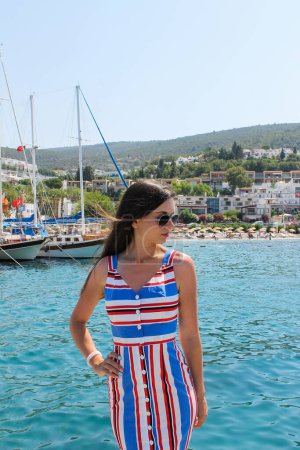 Beautiful young woman at the pier with boats and yachts in summer Turkey