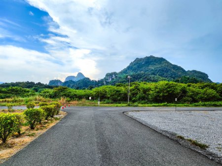A beautiful Scenic view of the mountain with leading line road with cloudy blue sky background at tasik timah tasoh, perlis, malaysia.