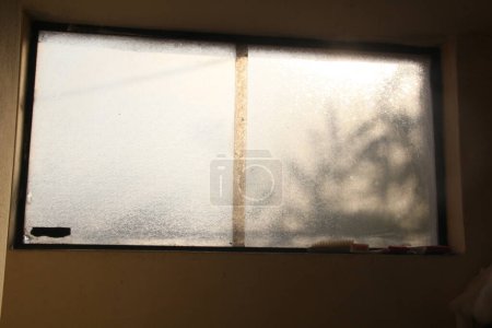 Sonnenbeschienene Silhouette: Ein geschlossenes Fenster in orangefarbenes Licht getaucht