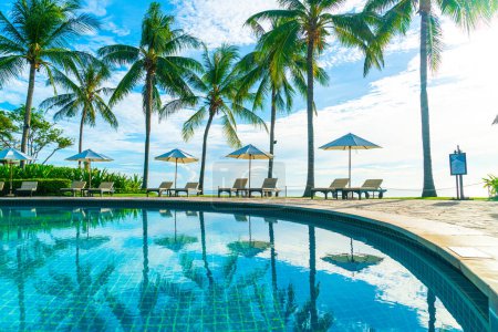 Téléchargez les photos : Superbe parasol de luxe et chaise autour de la piscine extérieure à l'hôtel et station balnéaire avec cocotier au coucher du soleil ou au lever du soleil - concept vacances et vacances - en image libre de droit
