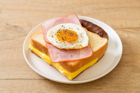 homemade bread toasted cheese topped ham and fried egg with pork sausage for breakfast