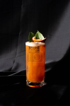 cocktail - infused tequila with basil, passion fruit and cinnamon, lime and mango in glass on dark background