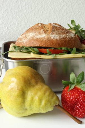 Gesunde Pause: Umweltfreundliche Lunchbox mit Roggen-Sandwich, Obst und digitalen Geräten