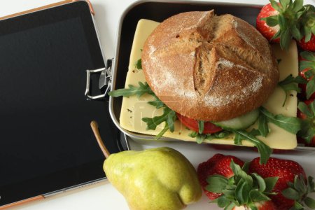 Healthy Break: Eco-Friendly Lunchbox with Rye Sandwich, Fruit, and Digital Device