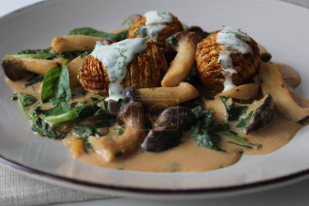 Artisanal Delight: Hasselback Potatoes on a Bed of Vegan Cream Sauce with Oyster Mushrooms and Spinach