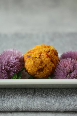 Couscous-Feta Balls with Chive Blossoms on Neutral Grey Background