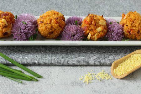 Couscous-Feta Balls with Chive Blossoms on Neutral Grey Background