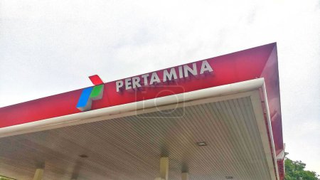 Foto de Kediri, Java Oriental. Indonesia - 02 de diciembre de 2023. Tablero de logotipo de Pertamina en gasolinera con cielo nuboso blanco durante el día. - Imagen libre de derechos