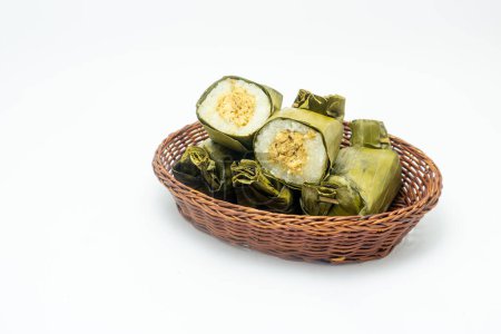 Alimento tradicional indonesio llamado lemper hecho de arroz glutinoso al vapor con carne de pollo envuelta en hojas de plátano, plato en canasta de ratán aislado sobre fondo blanco