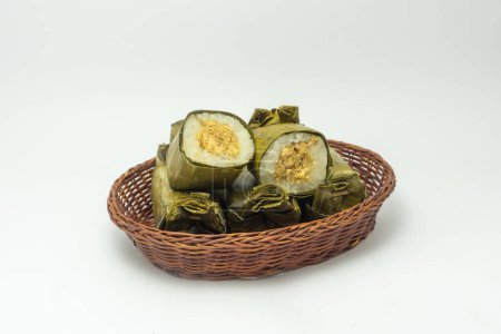 Indonesische traditionelle Lebensmittel namens Lemmer aus gedämpftem klebrigen Reis mit Hühnerfleisch in Bananenblättern gewickelt, Teller auf Rattankorb isoliert auf weißem Hintergrund