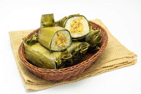 Indonesisches traditionelles Essen namens Lemmer aus gedämpftem klebrigem Reis mit Hühnerseide in Bananenblätter gewickelt, serviert auf Rattankorb.