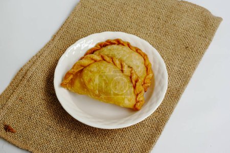 Karipap ou "bouffée de curry" ou jalangkote ou pastel rempli de garnitures de pommes de terre sur plaque blanche isolation sur fond blanc.