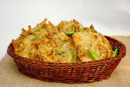 Selective focus Bakwan sayur or Bakwan Goreng or bala-bala or ote-ote is vegetebles fritter from Indonesia, served with cayenne peppers on rattan basket.