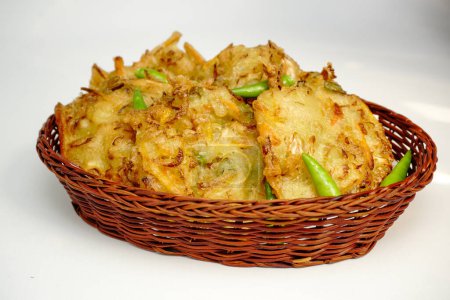 Enfoque selectivo Bakwan sayur o Bakwan Goreng o bala-bala o ote es un buñuelo de verduras de Indonesia, servido con pimientos de cayena en canasta de ratán.