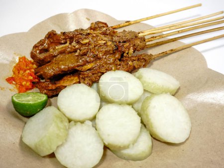 Sate Ayam (Chicken Satay) mit Erdnusssoße und Lontong (Reiskuchen). Eines der beliebtesten Streetfood Indonesiens. Selektiver Fokus.