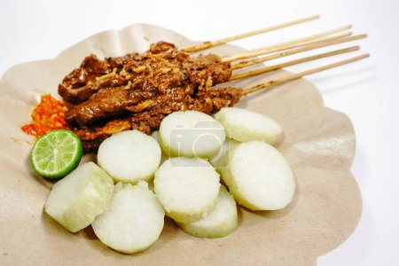 Sate Ayam (Chicken Satay) mit Erdnusssoße und Lontong (Reiskuchen). Eines der beliebtesten Streetfood Indonesiens. Selektiver Fokus.