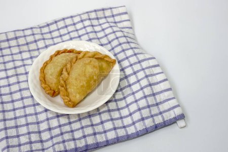 Karipap oder "Curry-Blätterteig" oder Jalangkote oder Pastell gefüllt mit Kartoffelfüllungen auf weißem Teller auf weißem Hintergrund. 