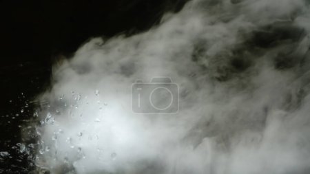 Foto de Las microgotas reales de agua caliente se pulverizan en el aire. nubes de un chorro grueso se arremolinan. niebla de humo seco. estado gaseoso. - Imagen libre de derechos