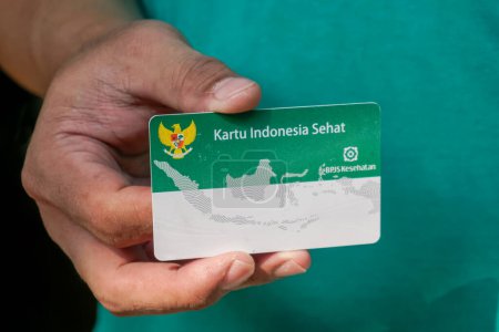 Mano con tarjeta de seguro de salud del gobierno indonesio o (Kartu BPJS Kesehatan o Kartu Indonesia Sehat)