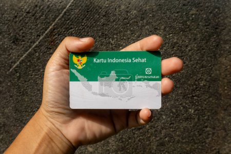 Hand holding Indonesian Government Health Insurance Card or (Kartu BPJS Kesehatan or Kartu Indonesia Sehat)