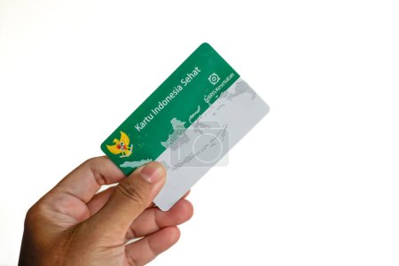 Hand holding Indonesian Government Health Insurance Card or (Kartu BPJS Kesehatan or Kartu Indonesia Sehat) isolated on white background, Jakarta - Indonesia, May 16, 2023