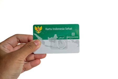 Hand holding Indonesian Government Health Insurance Card or (Kartu BPJS Kesehatan or Kartu Indonesia Sehat) isolated on white background, Yakarta - Indonesia, May 16, 2023